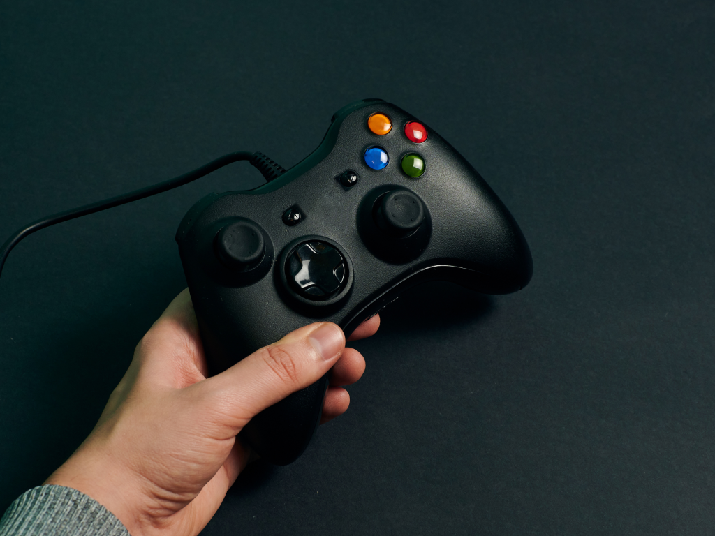 Hand holding a gaming controller over a black background.